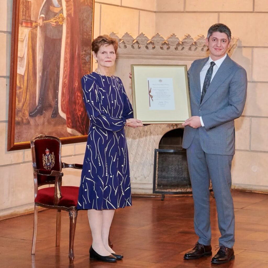 Ceremonie de înmânare a unui certificat înrămat într-o sală cu tablou istoric