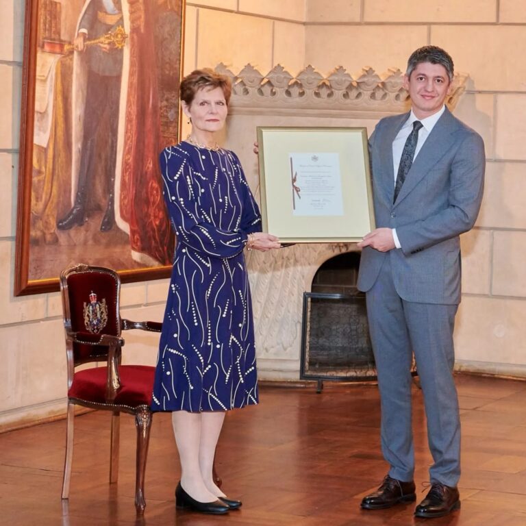 Ceremonie de înmânare a unui certificat înrămat într-o sală cu tablou istoric